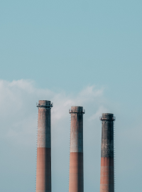 Three tall smokestacks or chimneys with smoke