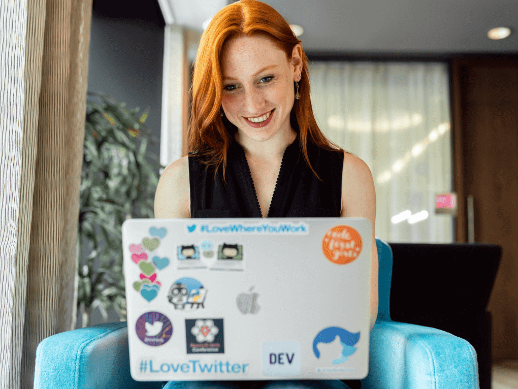 A woman smiling while working on a laptop